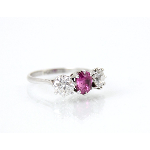 223 - An early 20th century pink sapphire and diamond three stone ring, the central oval cut pink stone wi... 