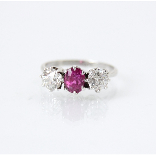 223 - An early 20th century pink sapphire and diamond three stone ring, the central oval cut pink stone wi... 