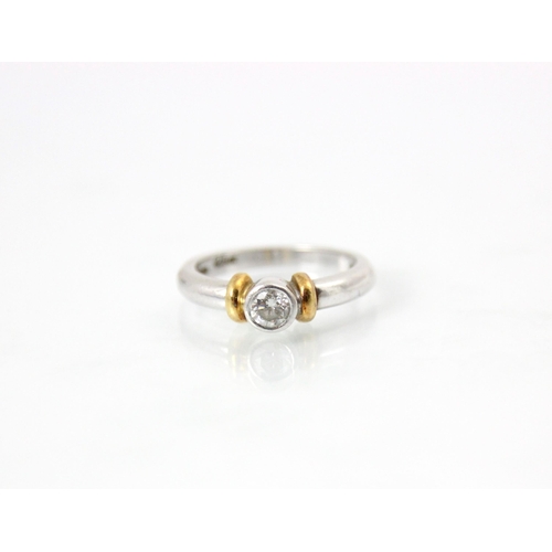 225 - A platinum and diamond solitaire ring, the central round cut diamond within a rubover setting edge, ... 