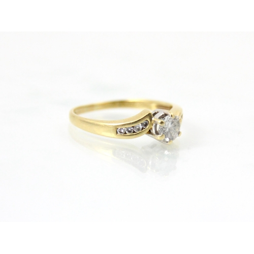 249 - A diamond solitaire ring, the central round cut diamond within yellow gold mount with diamond set sh... 