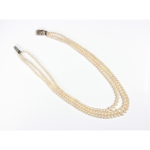 283 - A triple strand of pearls, the graduated pearls of non uniform form, upon an associated marcasite se... 