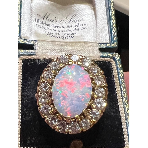 308 - An opal and diamond cluster ring, the large precious opal oval cabochon claw set with a surround of ... 