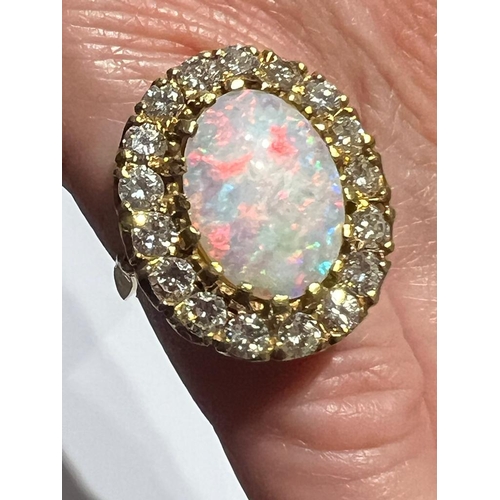 308 - An opal and diamond cluster ring, the large precious opal oval cabochon claw set with a surround of ... 