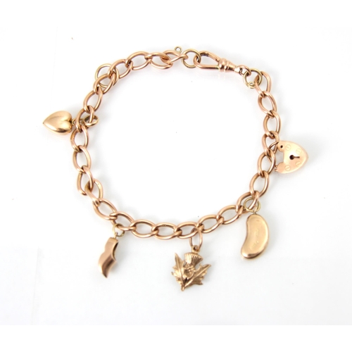 311 - A yellow metal charm bracelet, the curb links suspending five gold coloured charms including thistle... 