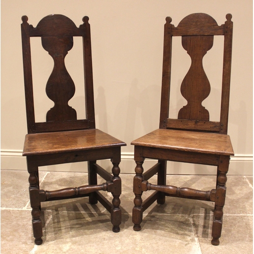 908 - A pair of 18th century oak side chairs, the vase shaped splats above a board seat, upon block and bo... 