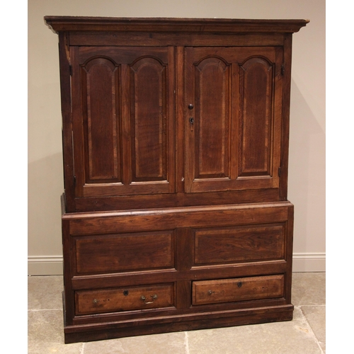 909 - An 18th century oak livery cupboard, the moulded cornice over a pair of fielded panelled cupboard do... 