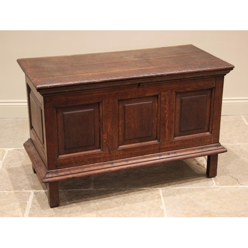 910 - An 18th century oak coffer, the hinged cover over three inverted panels and a moulded apron, upon st... 