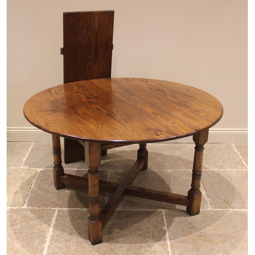 911 - An 18th century style oak draw leaf dining table, late 20th century, the circular top with additiona... 