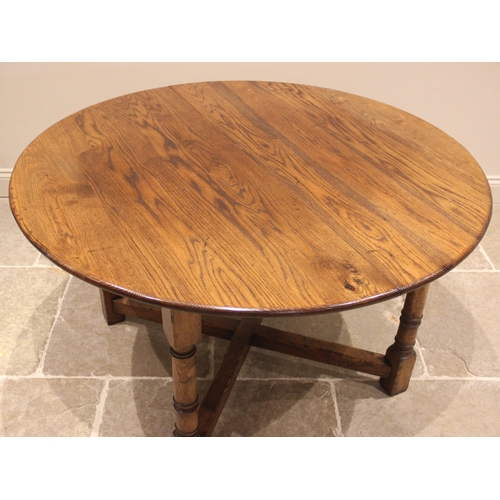 911 - An 18th century style oak draw leaf dining table, late 20th century, the circular top with additiona... 