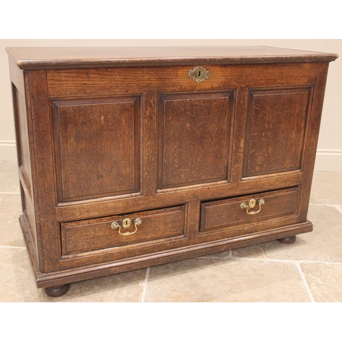 915 - An 18th century oak mule chest, the hinged cover over three front panels and a pair of drawers appli... 