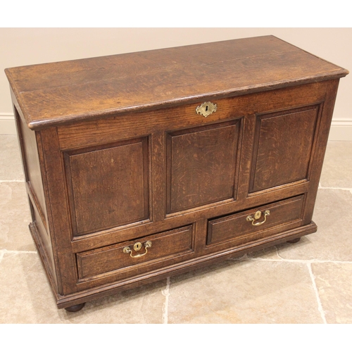 915 - An 18th century oak mule chest, the hinged cover over three front panels and a pair of drawers appli... 