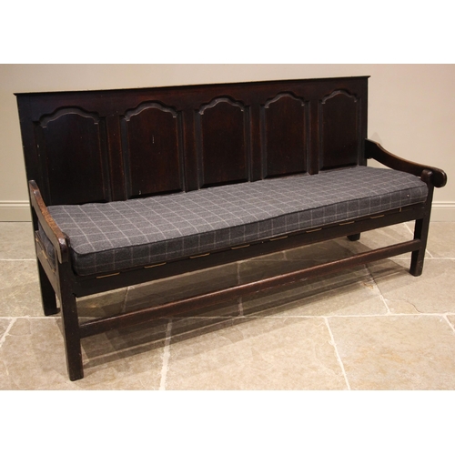 944 - A George III oak panel back settle, the five fielded panels extending to down swept arms upon legs o... 