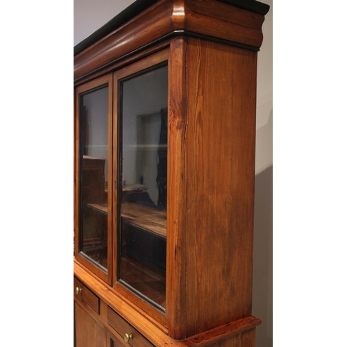 977 - A pitch pine glazed bookcase, late 19th century, the ogee moulded cornice embellished with ebonised ... 