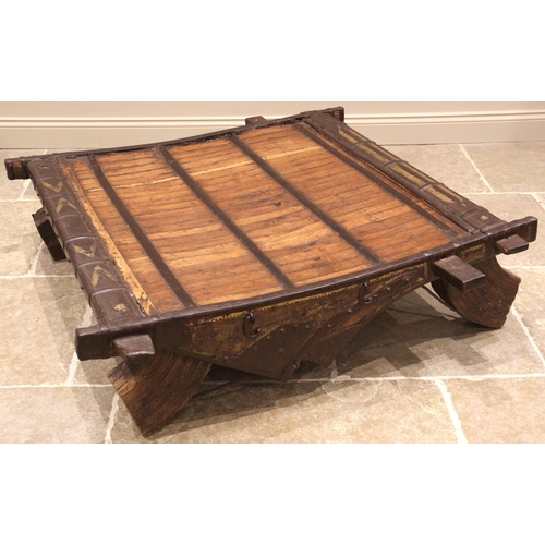 978 - A 19th century iron bound hardwood coffee table, formed from an elephant saddle, upon substantial sp... 