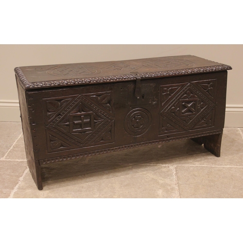 905 - A 17th century carved oak six plank coffer, the hinged cover carved with geometric motifs within a g... 