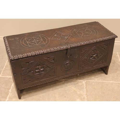 905 - A 17th century carved oak six plank coffer, the hinged cover carved with geometric motifs within a g... 