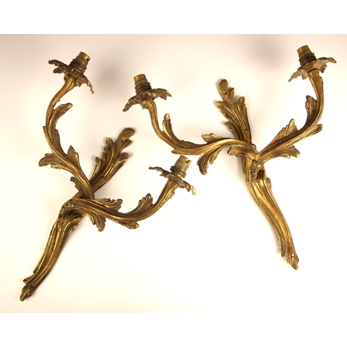 952 - A pair of twin branch gilt brass Rococo style wall sconces, 20th century, modelled as intwined acant... 