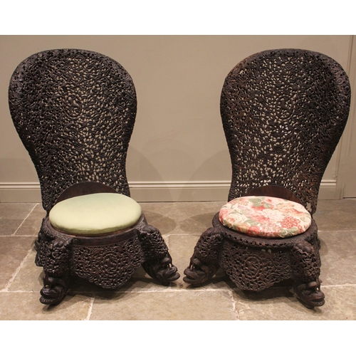 1027 - A pair of Anglo Indian carved chairs, circa 1880, each with a pierced and rounded high back, carved ... 