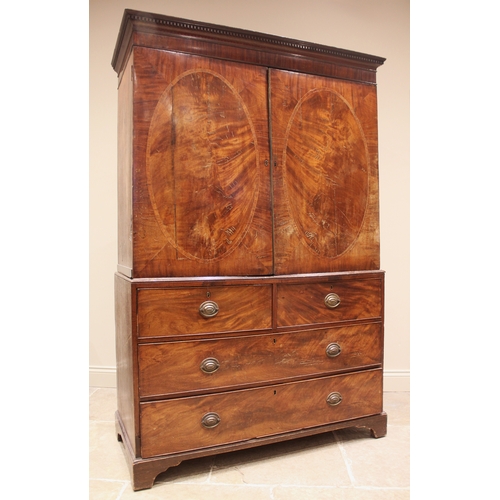 938 - A George III mahogany linen press, with a moulded dentil cornice over a pair of oval banded doors, o... 