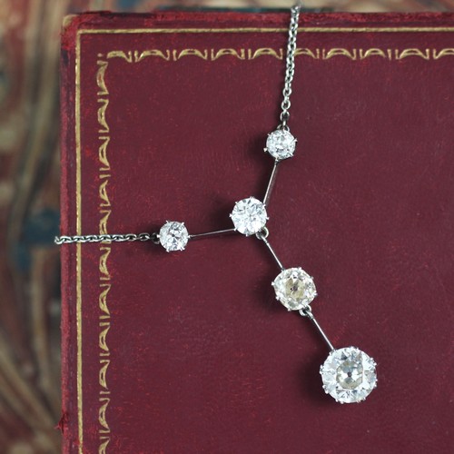 250 - An early 20th century negligee style set necklace, the row of three old cut diamonds separated by a ... 