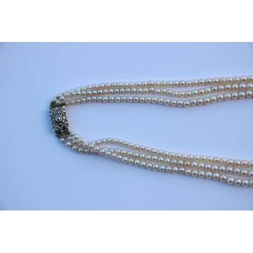 283 - A triple strand of pearls, the graduated pearls of non uniform form, upon an associated marcasite se... 