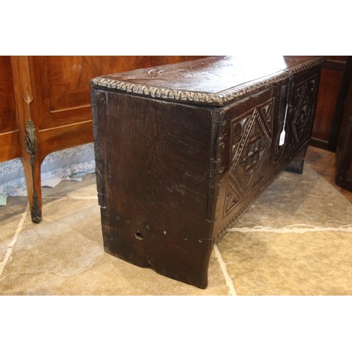 905 - A 17th century carved oak six plank coffer, the hinged cover carved with geometric motifs within a g... 