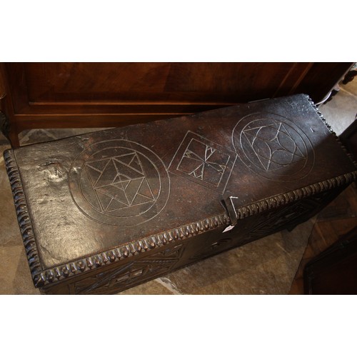 905 - A 17th century carved oak six plank coffer, the hinged cover carved with geometric motifs within a g... 