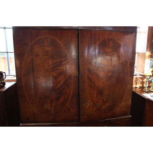 938 - A George III mahogany linen press, with a moulded dentil cornice over a pair of oval banded doors, o... 