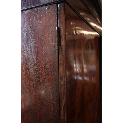 938 - A George III mahogany linen press, with a moulded dentil cornice over a pair of oval banded doors, o... 