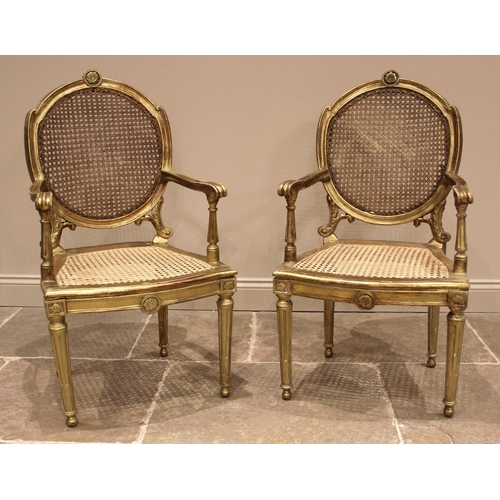 1002 - A pair of Louis XVI style gilt wood and cane work fauteuils, 19th century, each with a flower head r... 