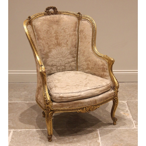 1011 - A French Louis XV style gilt wood bergère armchair, 20th century, the frame relief carved with rose ... 