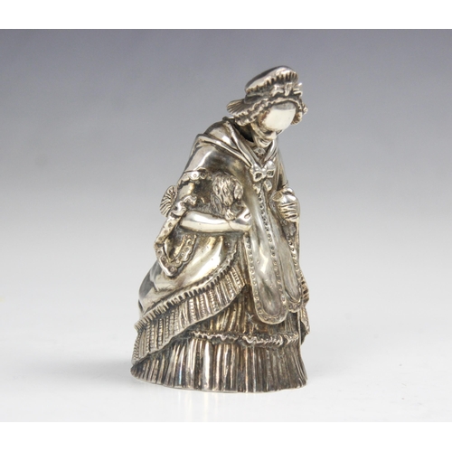 104 - A 20th century white metal novelty table bell, modelled as a well-dressed lady holding a dog and wal... 