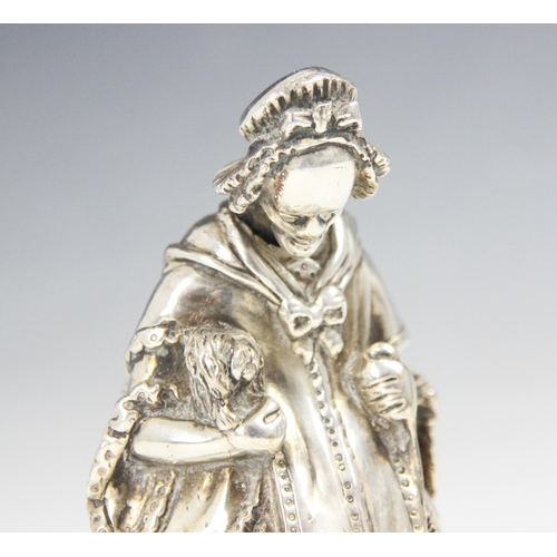 104 - A 20th century white metal novelty table bell, modelled as a well-dressed lady holding a dog and wal... 