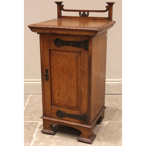 1047 - An Arts & Crafts oak pot cupboard, by Wylie and Lochhead, Glasgow, the open work top rail above a re... 