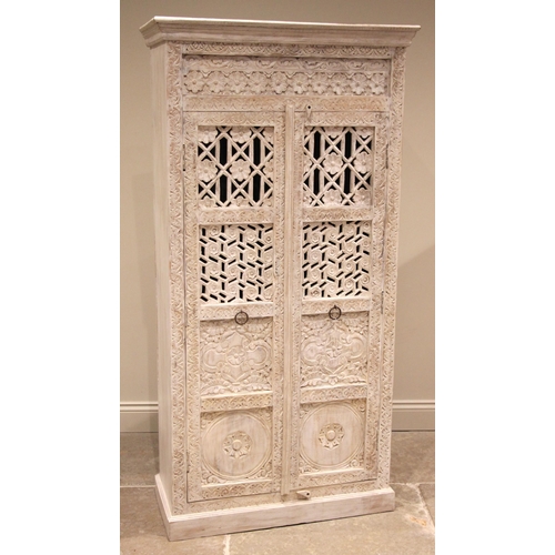 1070 - A painted and carved Indian hardwood cupboard, late 20th century, the moulded cornice over a pair of... 