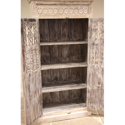 1070 - A painted and carved Indian hardwood cupboard, late 20th century, the moulded cornice over a pair of... 