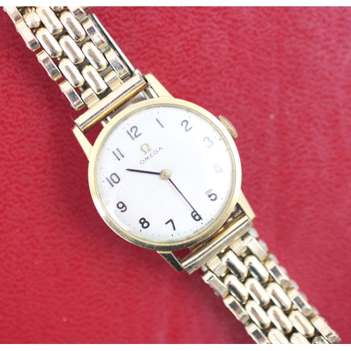 203 - A yellow metal Omega wristwatch, the circular cream dial with Arabic numerals, set to plain polished... 