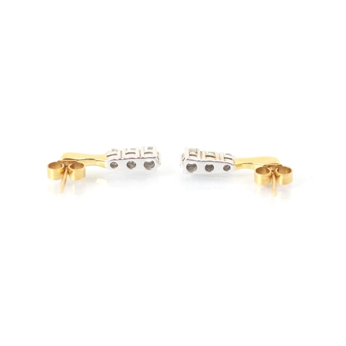 229 - A pair of diamond trilogy earrings, the yellow metal stud suspending three graduated round cut diamo... 