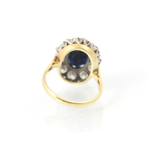 253 - An Edwardian style sapphire and diamond cluster ring, the central oval cut sapphire claw set in whit... 