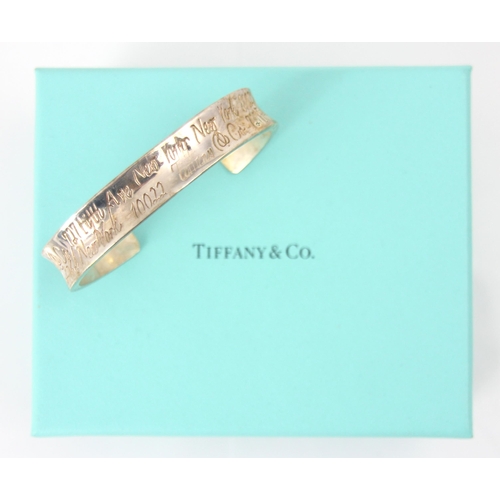 261 - A Tiffany and Co silver cuff style bangle, the concave exterior with engraved writing throughout, in... 