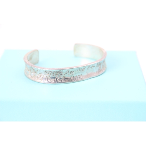 261 - A Tiffany and Co silver cuff style bangle, the concave exterior with engraved writing throughout, in... 