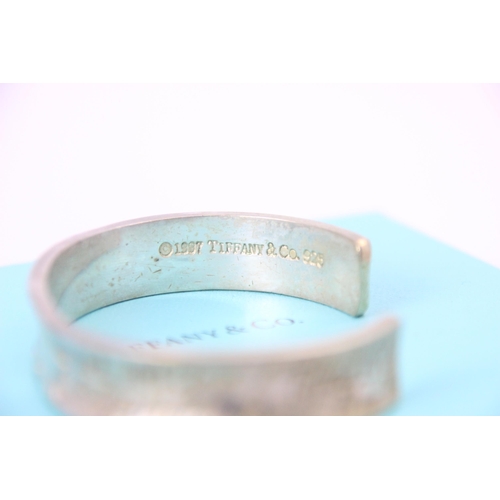 261 - A Tiffany and Co silver cuff style bangle, the concave exterior with engraved writing throughout, in... 