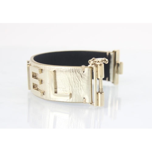 262 - A Chanel leather bracelet, the light gold toned cuff with applied CHANEL lettering, with slide lock ... 