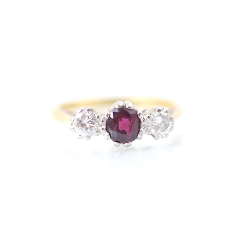 274 - An Edwardian style untested ruby and diamond three stone ring, the oval cut red stone within white m... 