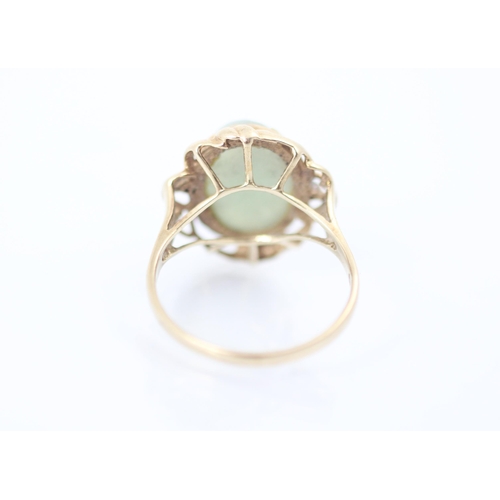 294 - A 9ct yellow gold green hardstone ring, the oval cabochon green stone within sinuous yellow gold mou... 