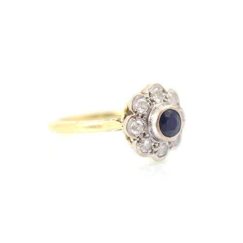 308 - A 20th century style sapphire and diamond cluster ring, the round cut sapphire within white metal ru... 