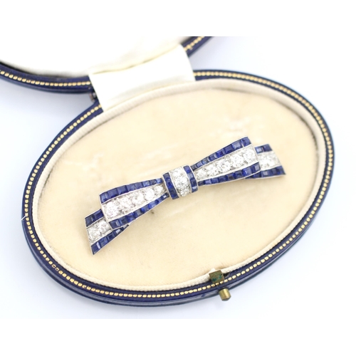 340 - An early 20th century sapphire and diamond ribbon brooch, the central line of old cut diamonds with ... 