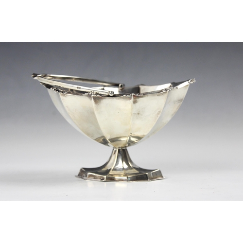 86 - An Edwardian silver sugar basket, ‘RH&S’ Birmingham 1901, the swing handle above fluted body, upon p... 