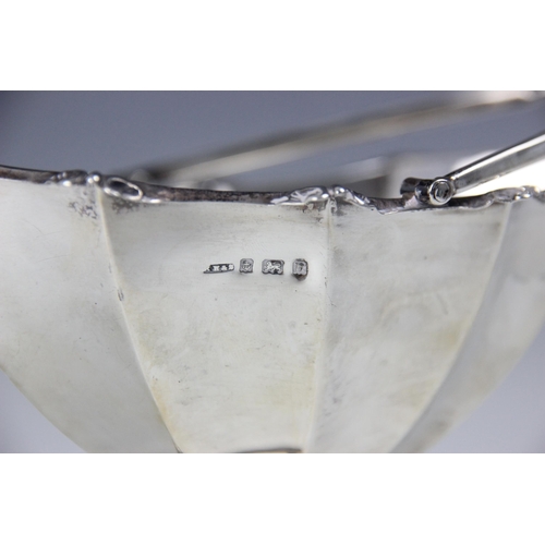 86 - An Edwardian silver sugar basket, ‘RH&S’ Birmingham 1901, the swing handle above fluted body, upon p... 