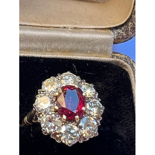 331 - An Edwardian style ruby and diamond cluster ring, the oval cut ruby within surround of eight round c... 